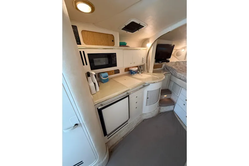 Slide: The Image of 1999 Sea Ray Sundancer 310 interior with kitchenette, microwave, and cozy sleeping area. - 27