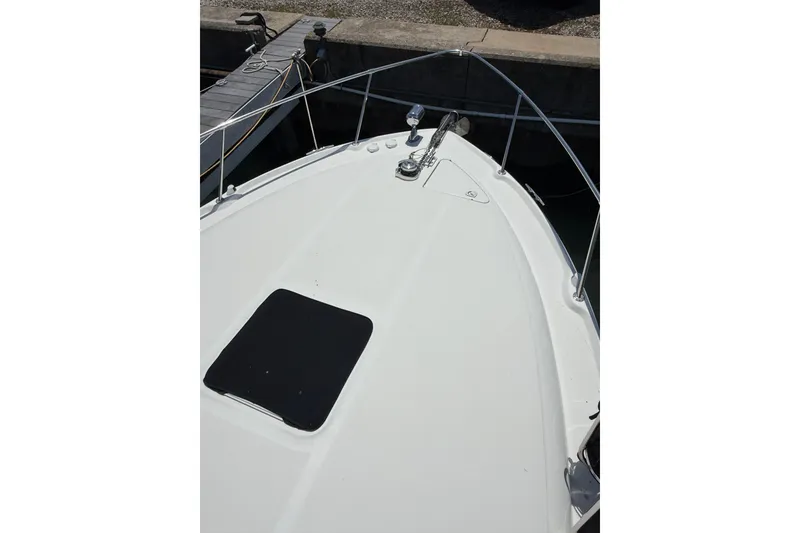 Slide: The Image of Bow view of a 1999 Sea Ray Sundancer 310 docked, featuring a sleek white deck. - 7
