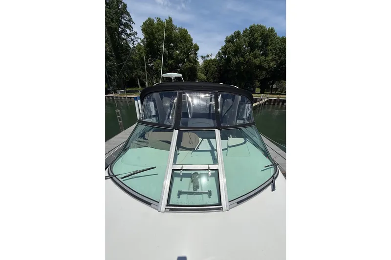 Slide: The Image of 1999 Sea Ray Sundancer 310 boat docked, featuring a sleek windshield and canopy. - 8