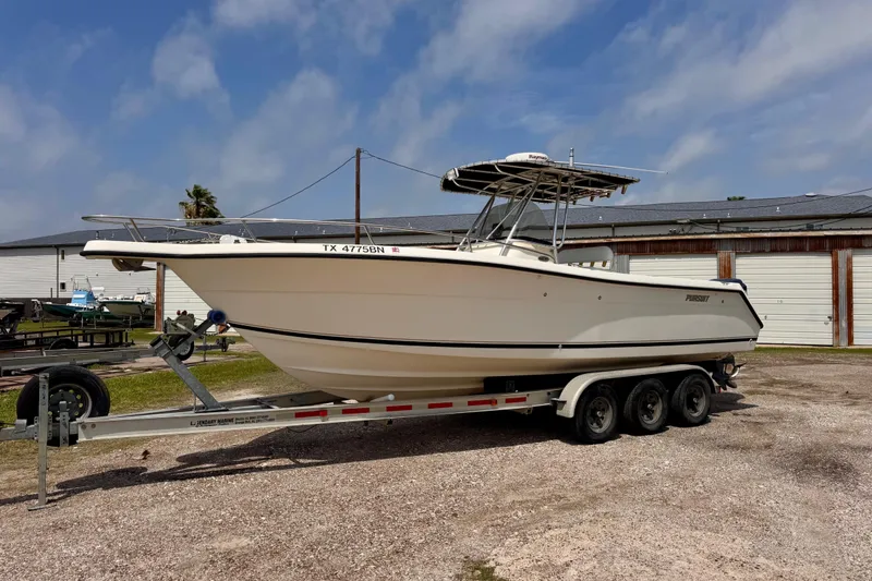 Slide: The Image of 2004 Pursuit 2670 Cuddy Console boat on a trailer, parked outdoors. - 1