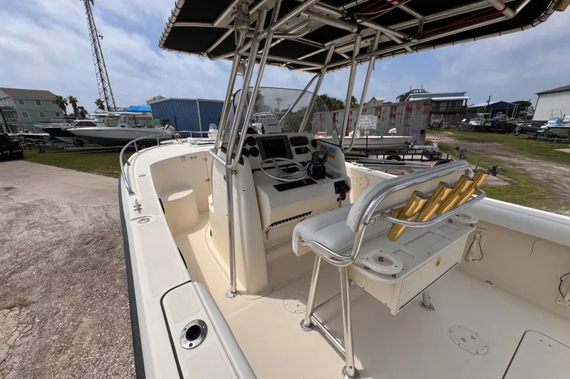 Slide: The Image of 2004 Pursuit 2670 Cuddy Console boat with helm, seating, and rod holders in a marina setting. - 21
