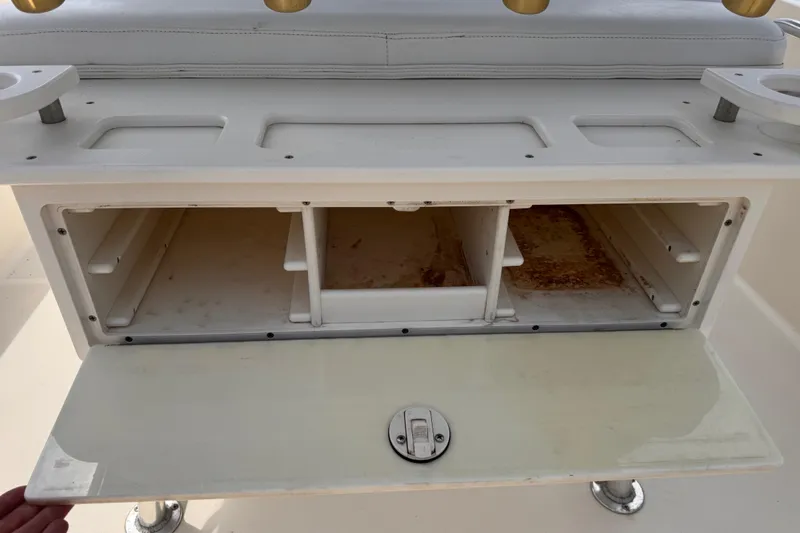 Slide: The Image of 2004 Pursuit 2670 Cuddy Console storage compartment with open hatch and rod holders. - 25