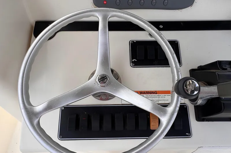 Slide: The Image of Close-up of a boat steering wheel and dashboard with switches and a warning label. - 27
