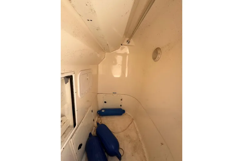 Slide: The Image of Interior of 2004 Pursuit 2670 Cuddy Console boat with storage compartments and blue fenders. - 38