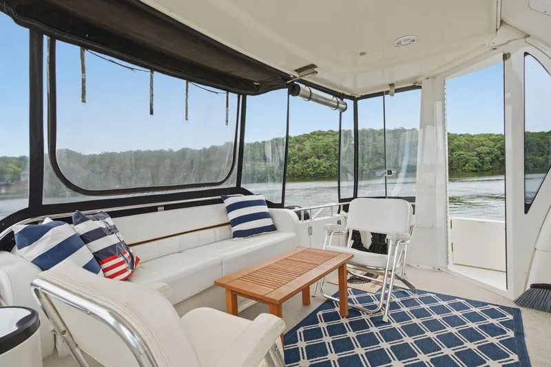 Slide: The Image of 2005 Carver 39 Motor Yacht interior with seating, striped pillows, and scenic water view. - 12
