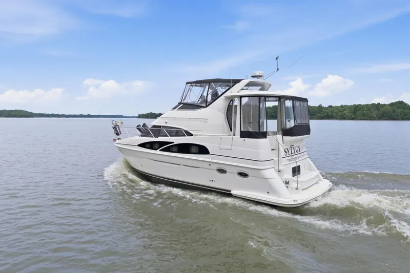 Slide: The Image of 2005 Carver 39 Motor Yacht cruising on a serene lake under a clear blue sky. - 2