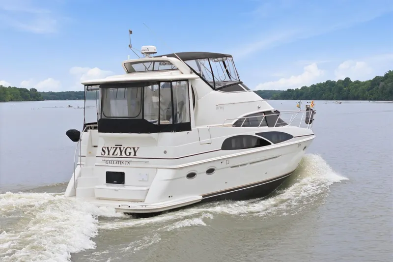 Slide: The Image of 2005 Carver 39 Motor Yacht cruising on a serene lake under a clear blue sky. - 5