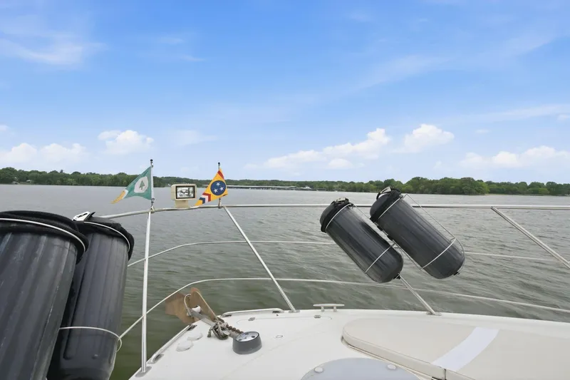 Slide: The Image of 2005 Carver 39 Motor Yacht on a serene lake with clear skies and flags. - 7