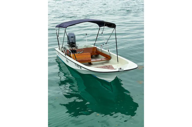 Slide: The Image of 1983 Boston Whaler 15 boat with canopy on calm water. - 2