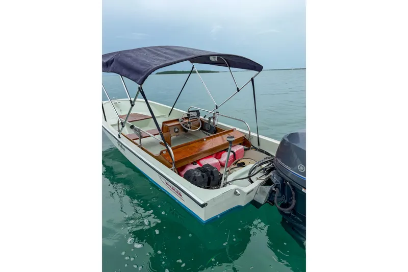 Slide: The Image of 1983 Boston Whaler 15 boat with canopy on calm water. - 6