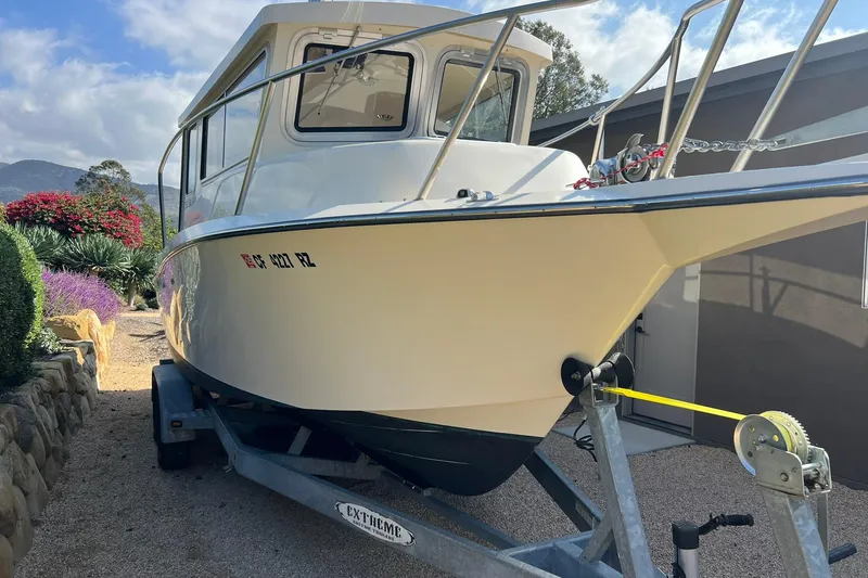 Slide: The Image of 2016 Defiance San Juan 250 boat on trailer, parked outdoors with scenic background. - 1
