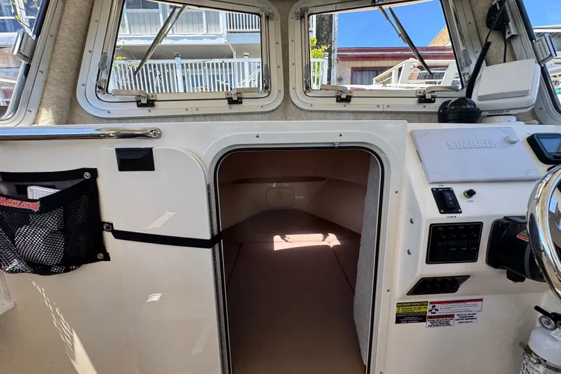 Slide: The Image of Interior cabin view of a 2016 Defiance San Juan 250 boat, featuring navigation controls. - 10