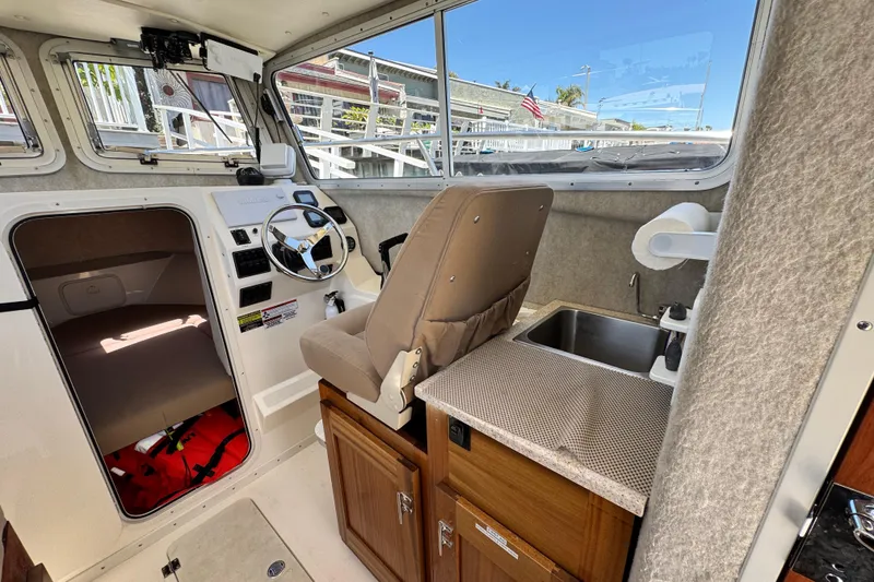 Slide: The Image of Interior of a 2016 Defiance San Juan 250 boat with steering wheel and kitchenette. - 11