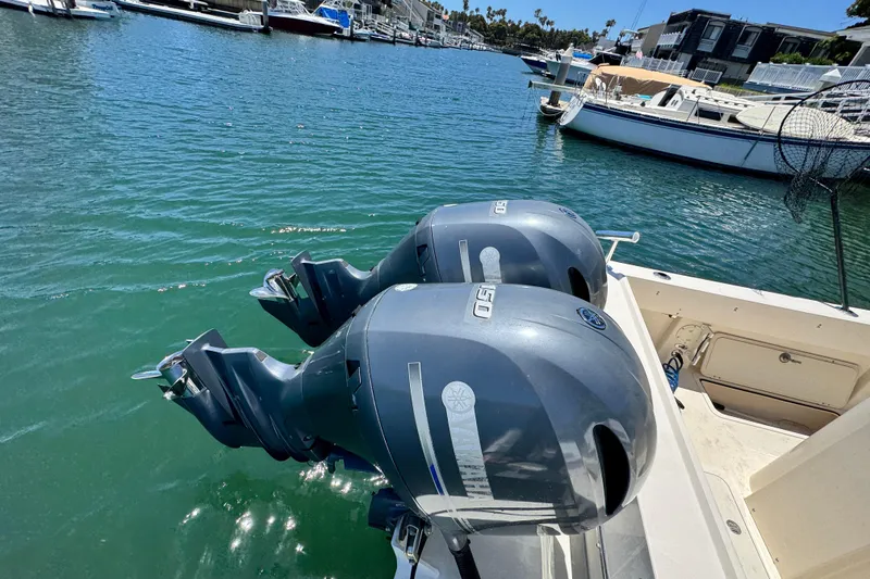 Slide: The Image of Twin outboard motors on a 2016 Defiance San Juan 250 boat in a marina. - 17