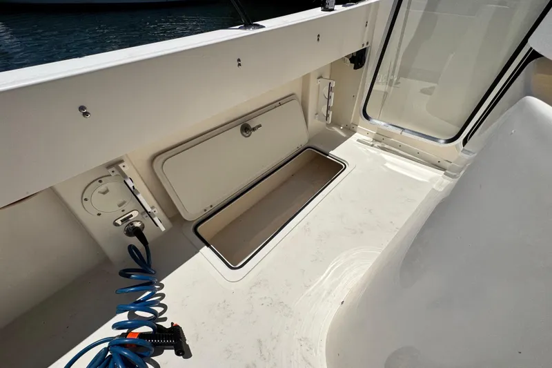 Slide: The Image of 2016 Defiance San Juan 250 boat deck with storage compartment and coiled hose. - 35