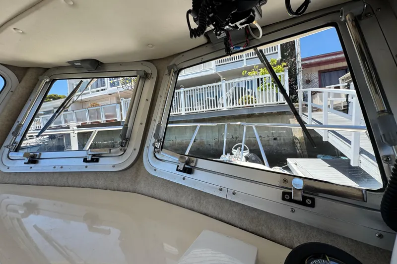 Slide: The Image of Interior view from a 2016 Defiance San Juan 250 boat, showing dockside scenery through windows. - 38