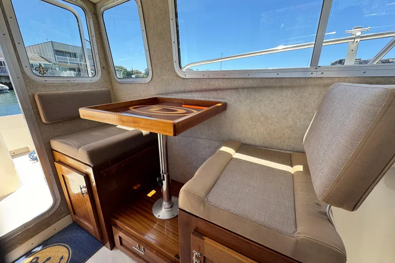 Slide: The Image of 2016 Defiance San Juan 250 boat interior with cushioned seating and wooden table. - 46