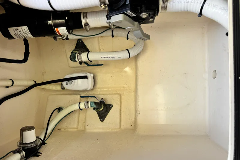 Slide: The Image of Bilge area of a 2016 Defiance San Juan 250 boat with visible plumbing and pump components. - 59