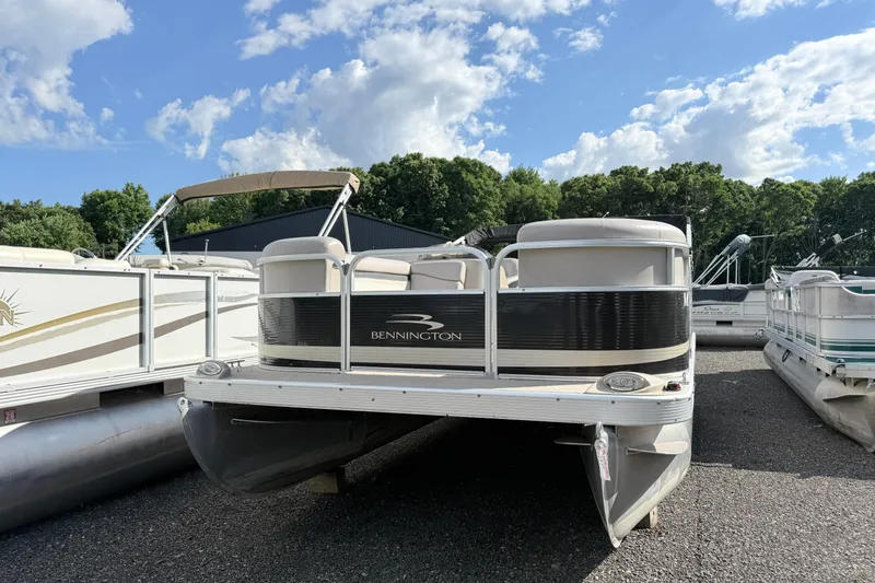 Slide: The Image of 2010 Bennington 20SLi pontoon boat parked outdoors under a blue sky. - 2
