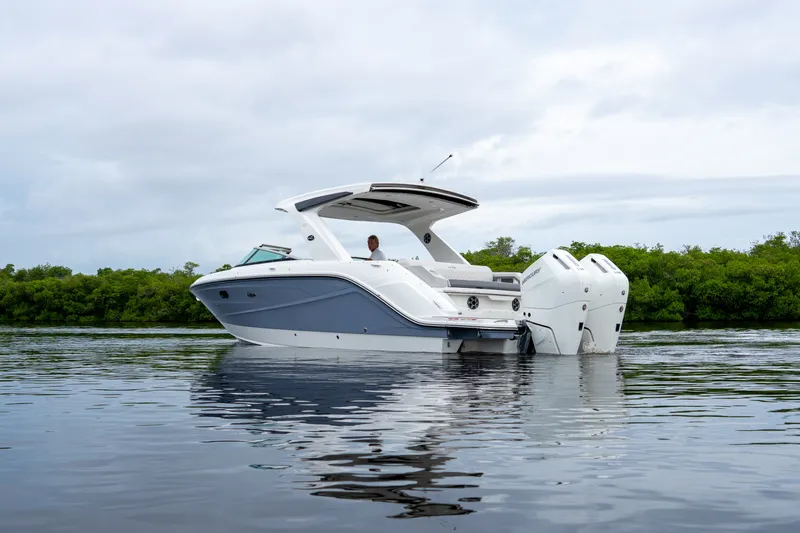 Slide: The Image of A modern 2027 Sea Ray SLX 310 Outboard on calm water, surrounded by green vegetation. - 33