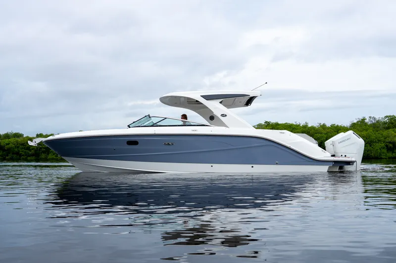 Slide: The Image of A sleek 2027 Sea Ray SLX 310 Outboard boat on calm water, surrounded by green vegetation. - 32