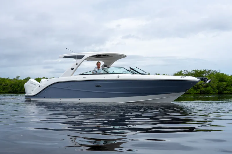Slide: The Image of A sleek Sea Ray SLX 310 Outboard boat on calm water with a driver on board. - 0