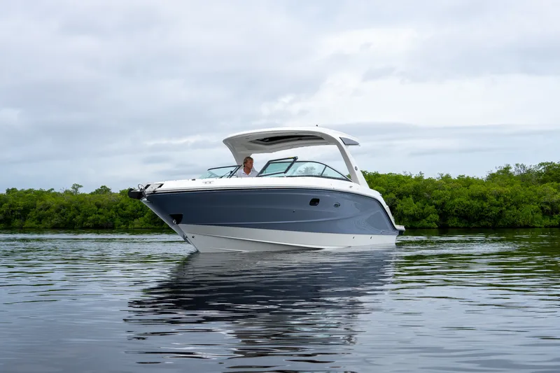 Slide: The Image of A modern 2027 Sea Ray SLX 310 Outboard on calm water, surrounded by green vegetation. - 30