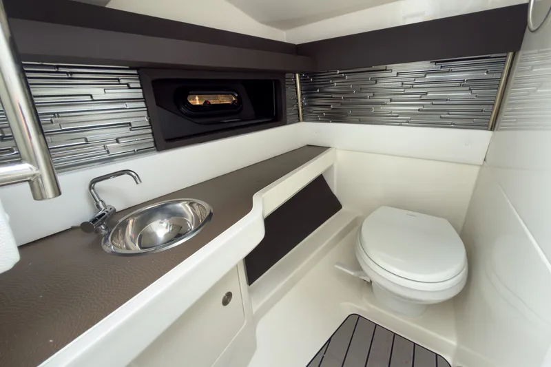 Slide: The Image of The cabin of the 2027 Sea Ray SLX 310 Outboard features a modern bathroom with a sink and toilet. - 19
