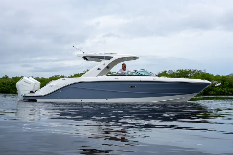 Slide: The Image of A sleek 2027 Sea Ray SLX 310 Outboard boat on calm water. - 27