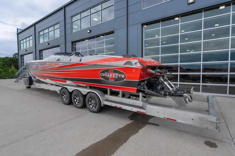 Slide: The Image of 2006 Cigarette 39' Top Gun Unlimited boat on trailer, parked outside modern building. - 23