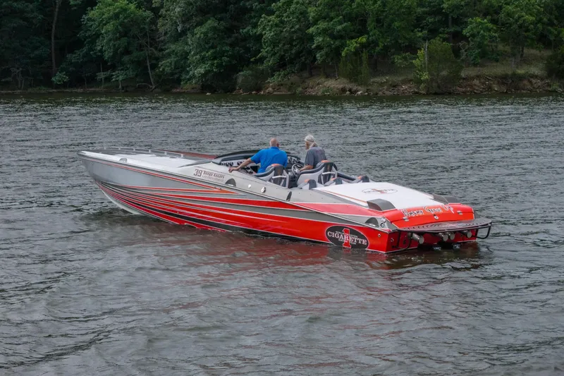 Slide: The Image of 2006 Cigarette 39' Top Gun speedboat on a lake with lush green shoreline. - 5