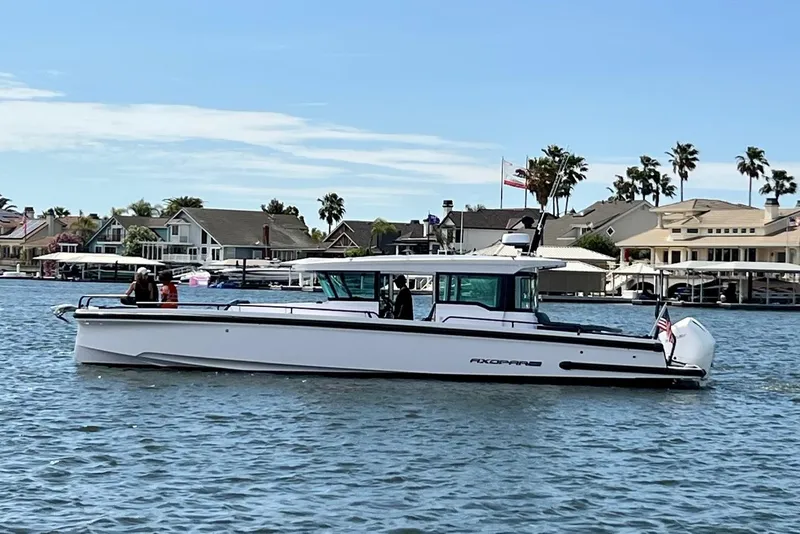 Slide: The Image of 2022 Axopar Brabus 37 XC Cross Cabin boat on a scenic waterfront. - 1