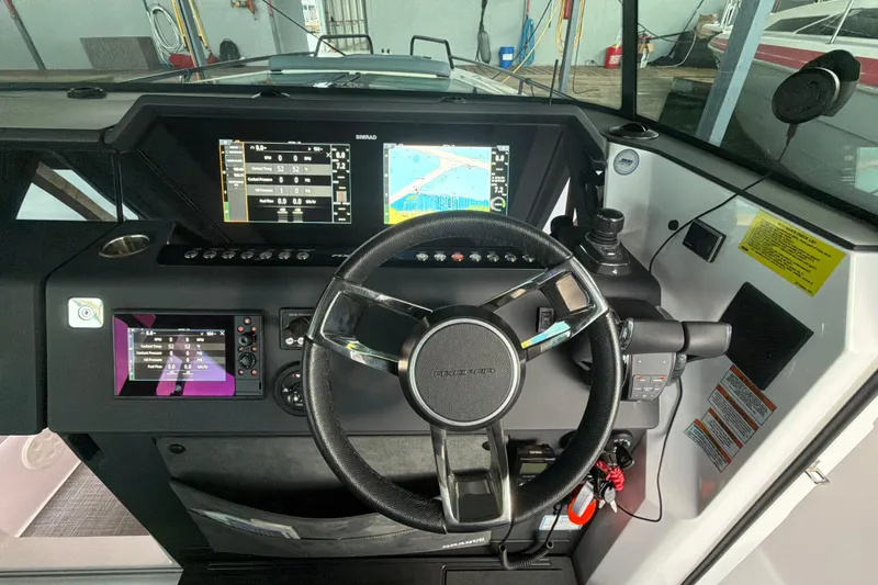 Slide: The Image of 2022 Axopar Brabus 37 XC Cross Cabin dashboard with steering wheel and navigation screens. - 15