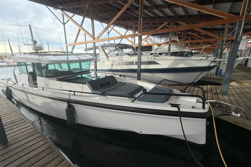 Slide: The Image of 2022 Axopar Brabus 37 XC Cross Cabin docked in a marina under a wooden roof. - 5