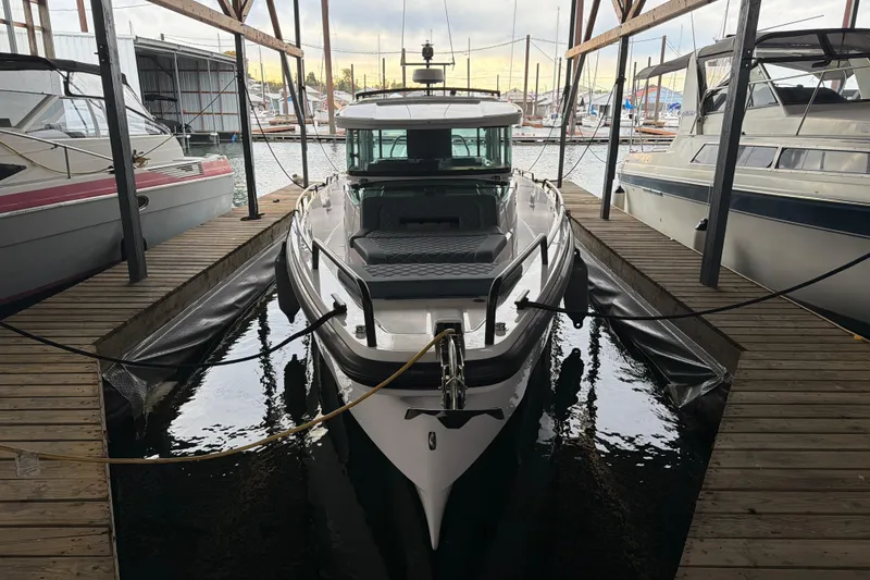 Slide: The Image of 2022 Axopar Brabus 37 XC Cross Cabin docked in a marina, surrounded by other boats. - 6