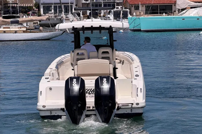 Slide: The Image of 2021 Boston Whaler 330 Outrage boat with dual engines in a marina setting. - 6