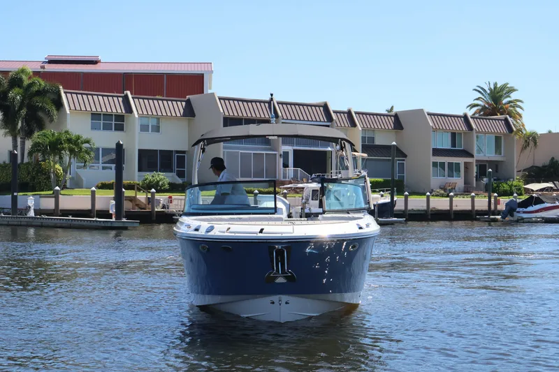 Slide: The Image of A 2027 Sea Ray SDX 270 Outboard cruising on a calm waterway in front of modern houses. - 11