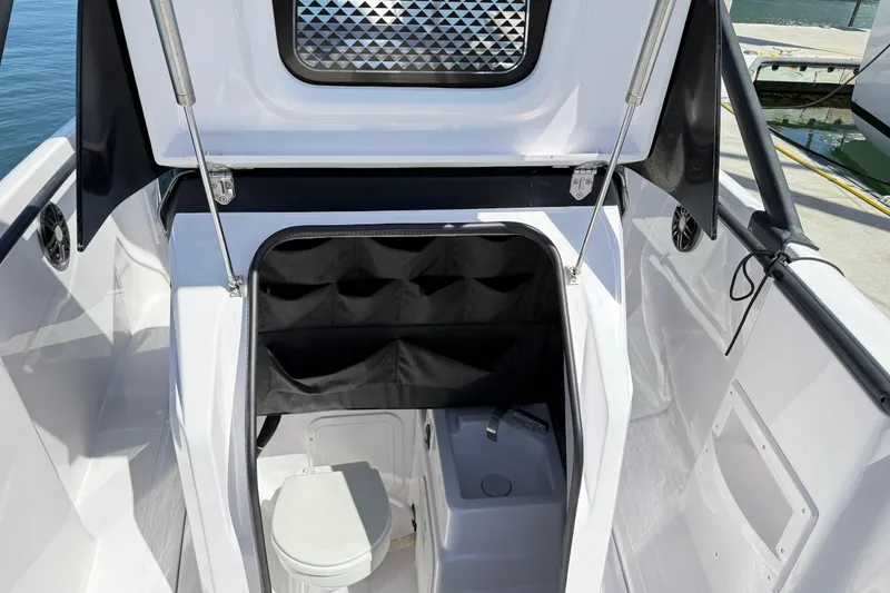 Slide: The Image of 2022 Axopar 22 T-Top boat interior with compact toilet and storage area. - 17