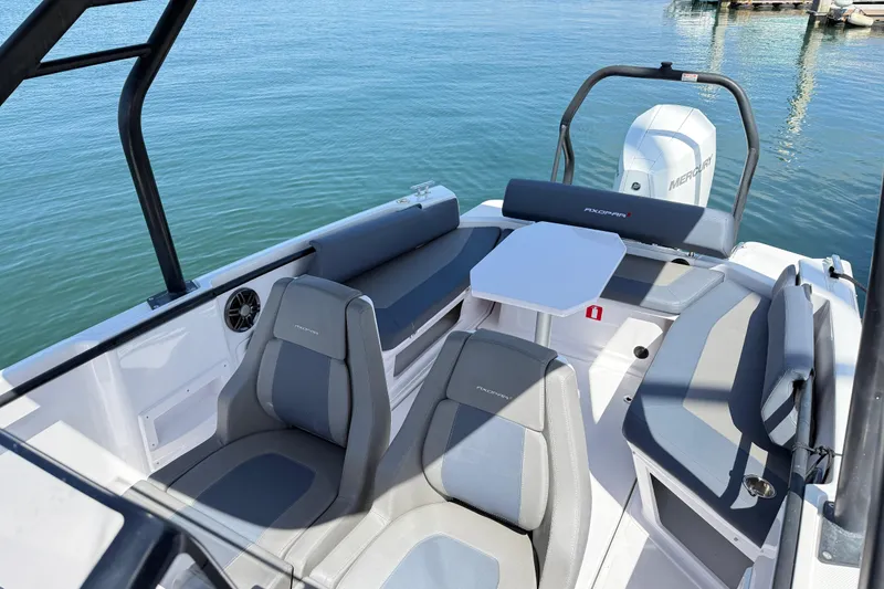 Slide: The Image of 2022 Axopar 22 T-Top boat interior with seating and table on calm water. - 24
