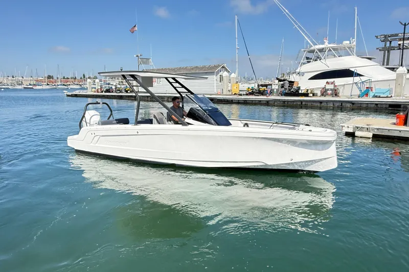 Slide: The Image of 2022 Axopar 22 T-Top boat docked in a marina, clear sky, calm water. - 25
