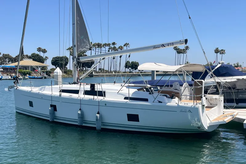 The Image of 2022 Hanse 418 sailboat docked in a sunny marina with palm trees. - 0