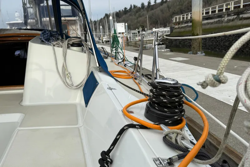 Slide: The Image of 1988 Ericson 32-200 sailboat docked, featuring deck ropes and winch, with marina background. - 16