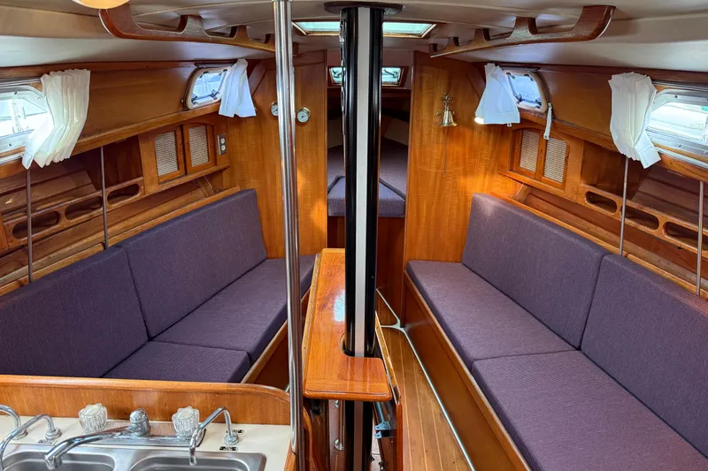 Slide: The Image of Interior of a 1988 Ericson 32-200 sailboat with wood finish and purple seating. - 23