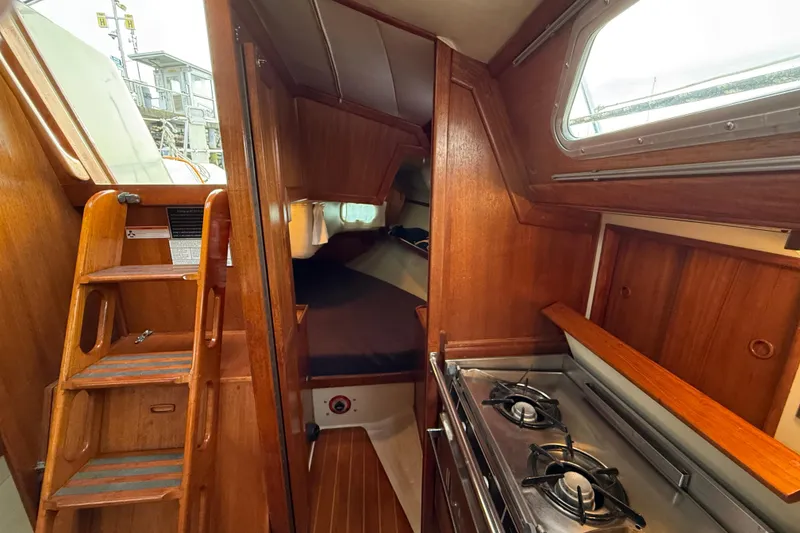 Slide: The Image of Interior of 1988 Ericson 32-200 sailboat with wooden cabinetry and compact kitchen. - 32