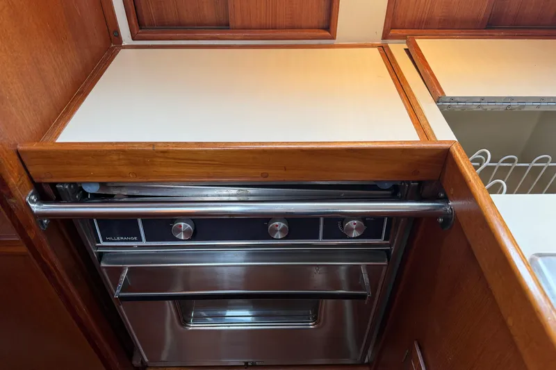 Slide: The Image of Ericson 32-200 (1988) yacht kitchen with Hillerange stove and wooden cabinetry. - 35
