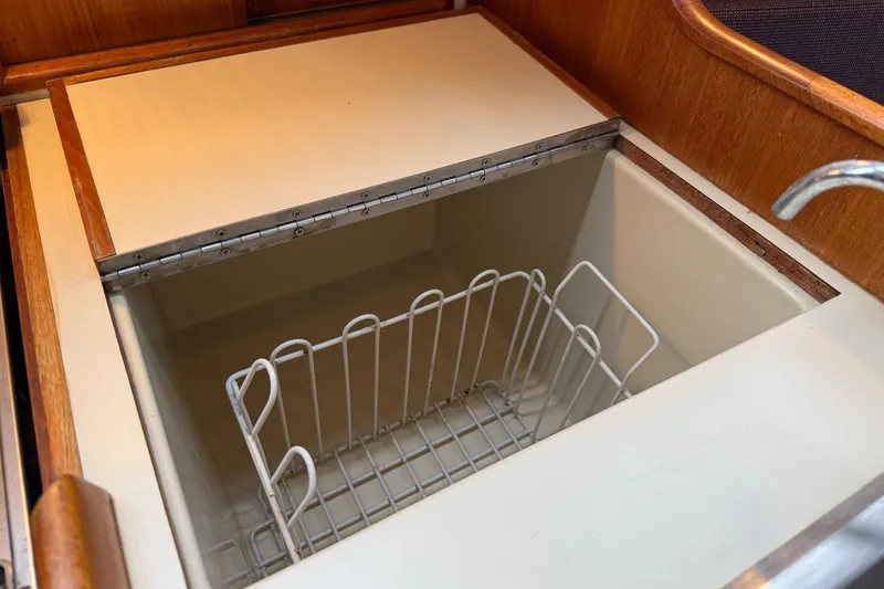 Slide: The Image of Built-in storage compartment on 1988 Ericson 32-200 sailboat, featuring a wire basket. - 36