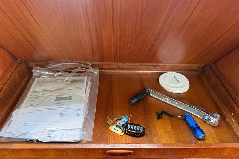 Slide: The Image of Wooden drawer with documents, keys, wrench, flashlight, and a lid on an Ericson 32-200, 1988. - 38