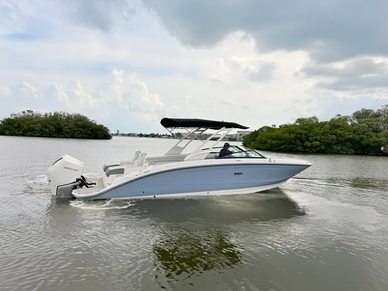 Slide: The Image of A sleek 2027 Sea Ray SDX 290 Outboard boat cruising on calm water with lush greenery in the background. - 12