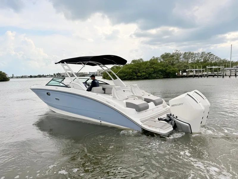 Slide: The Image of A 2027 Sea Ray SDX 290 Outboard cruising on calm waters. It features a sleek design with a black sunshade. - 21