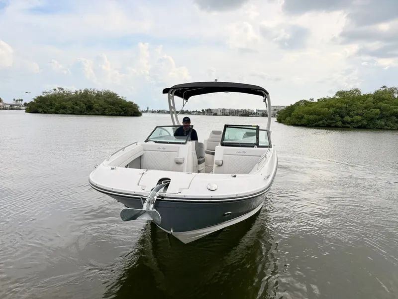 Slide: The Image of A 2027 Sea Ray SDX 290 Outboard on calm water. A person is seated at the helm. - 5